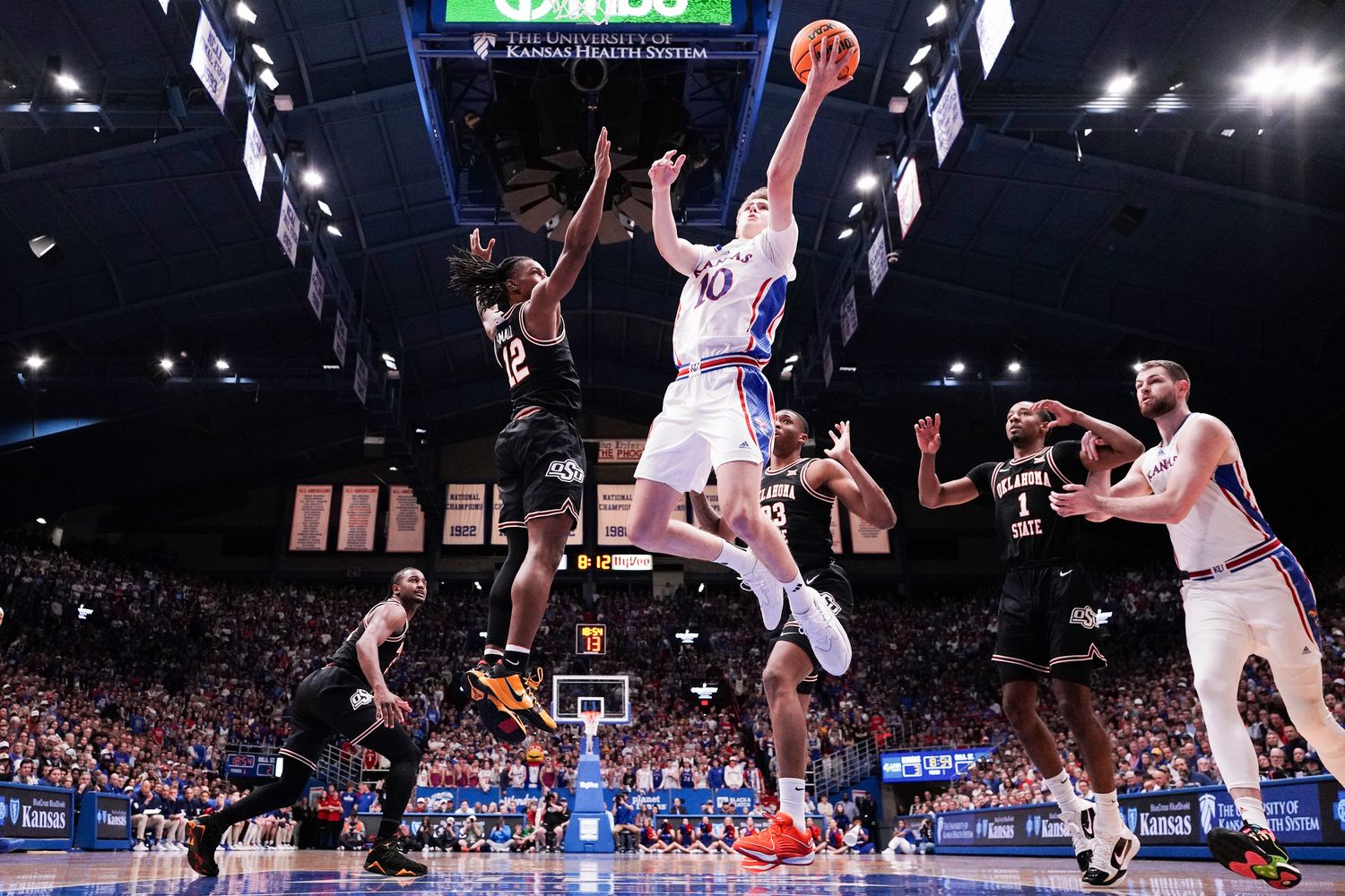 Jan 30, 2024; Lawrence, Kansas, USA; Kansas Jayhawks guard Johnny Furphy (10) shoots as Oklahoma State Cowboys guard Javon Small (12) defends during the first half at Allen Fieldhouse. Mandatory Credit: Denny Medley-USA TODAY Sports